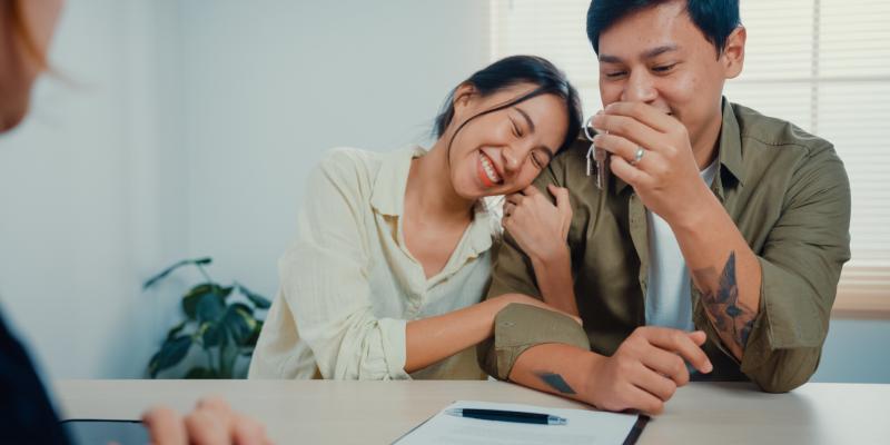 smiling homebuyers holding a house key in an office setting